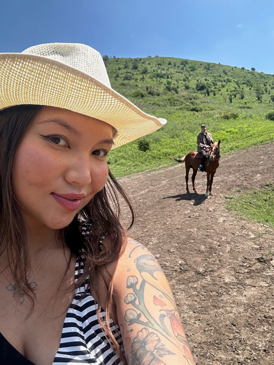 Guest in traditional Kazakh hat with horse rider in the background