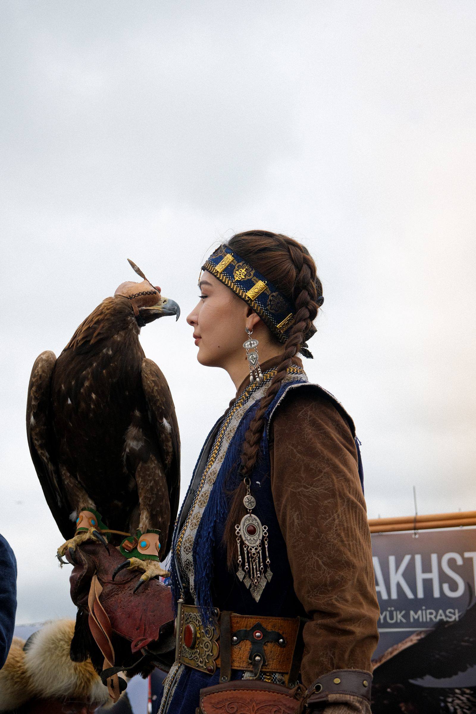 A Kazakh eagle hunter in traditional dress with a golden eagle on her arm