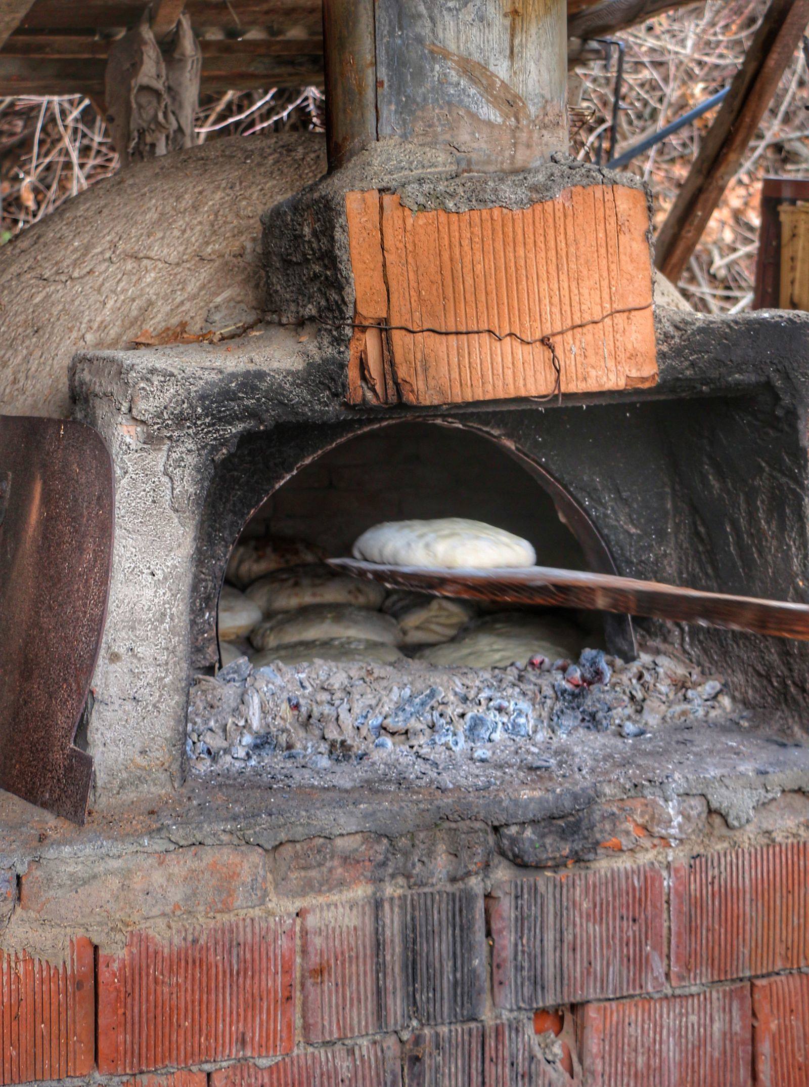 Artisan bread being prepared in an outdoor wood-fired oven