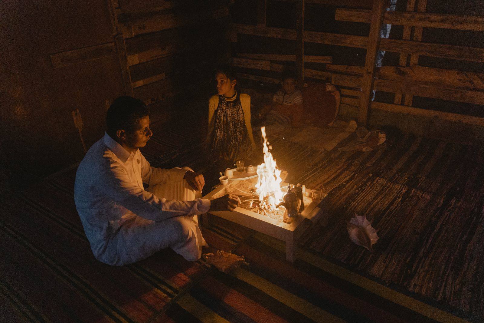 People gathered around a fire sharing a meal outdoors in the evening